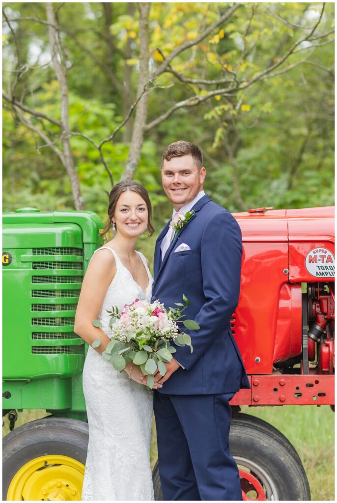 bride and groom posing in front of their green and red tractors in Bowling Green, Ohio
