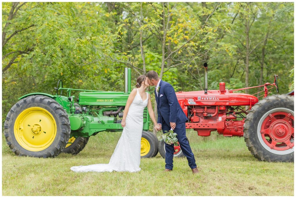 bride and groom share a kiss in front of their tractors in Bowling Green, Ohio