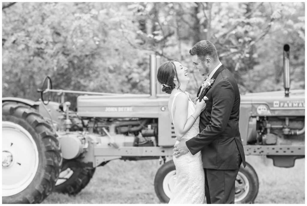 wedding couple laughing in front one of their tractors on their farm in Ohio
