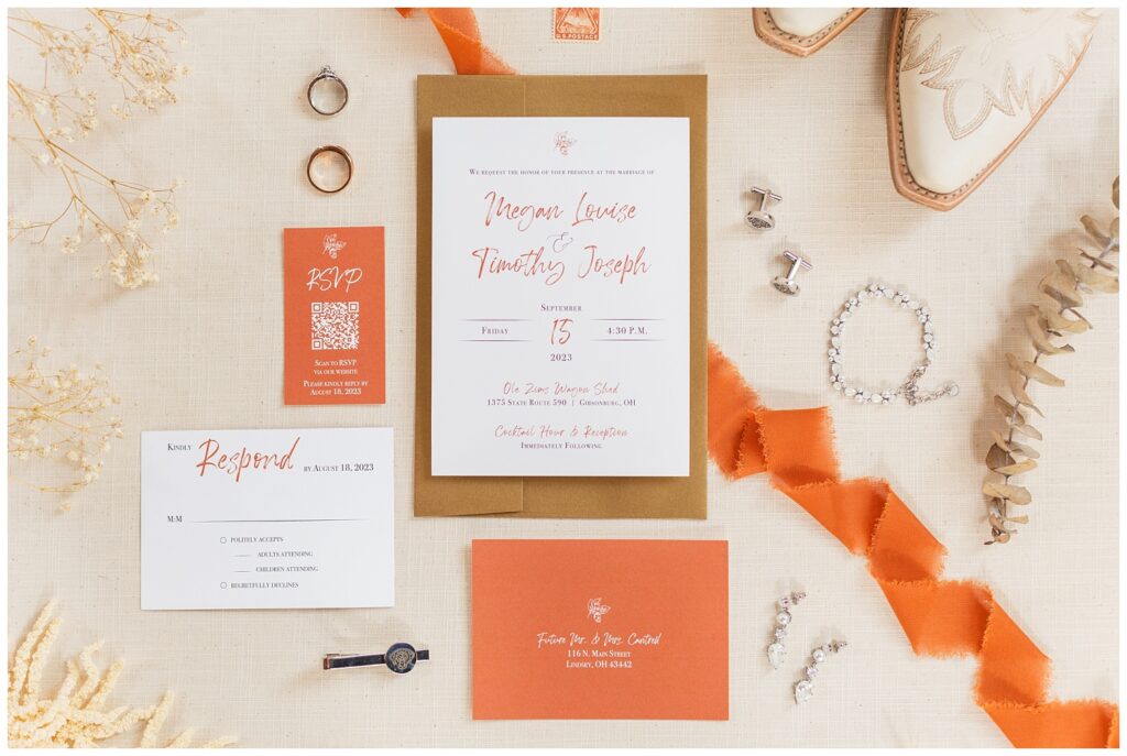 full wedding flat lay with invitation, white boots, and jewelry