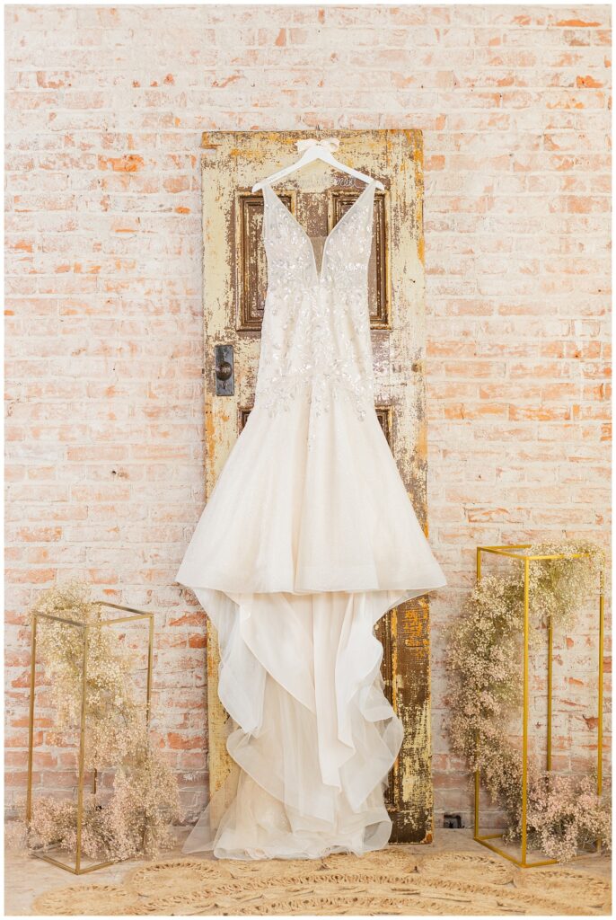 ivory wedding dress hanging from a old wooden antique door on a brick wall