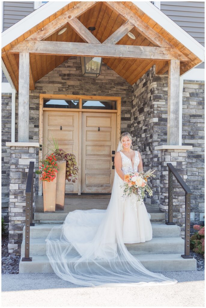 bride posing with bouquet on the front steps of wedding venue