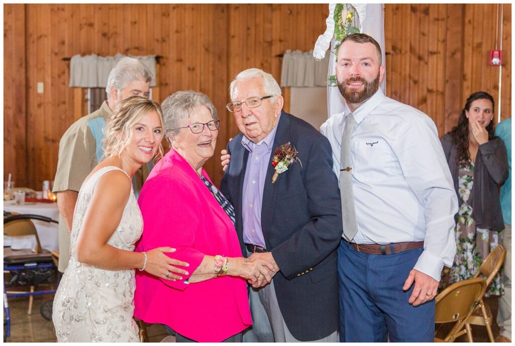bride and groom pose with grandparents at wedding reception