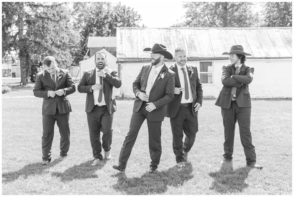 groomsmen laughing and walking in front of a white barn in northwest Ohio
