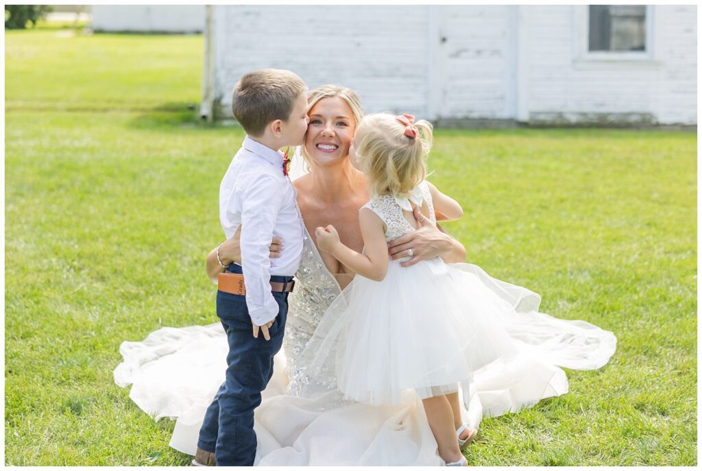 flower girl and ring bearer giving the bride a kiss at fall wedding 
