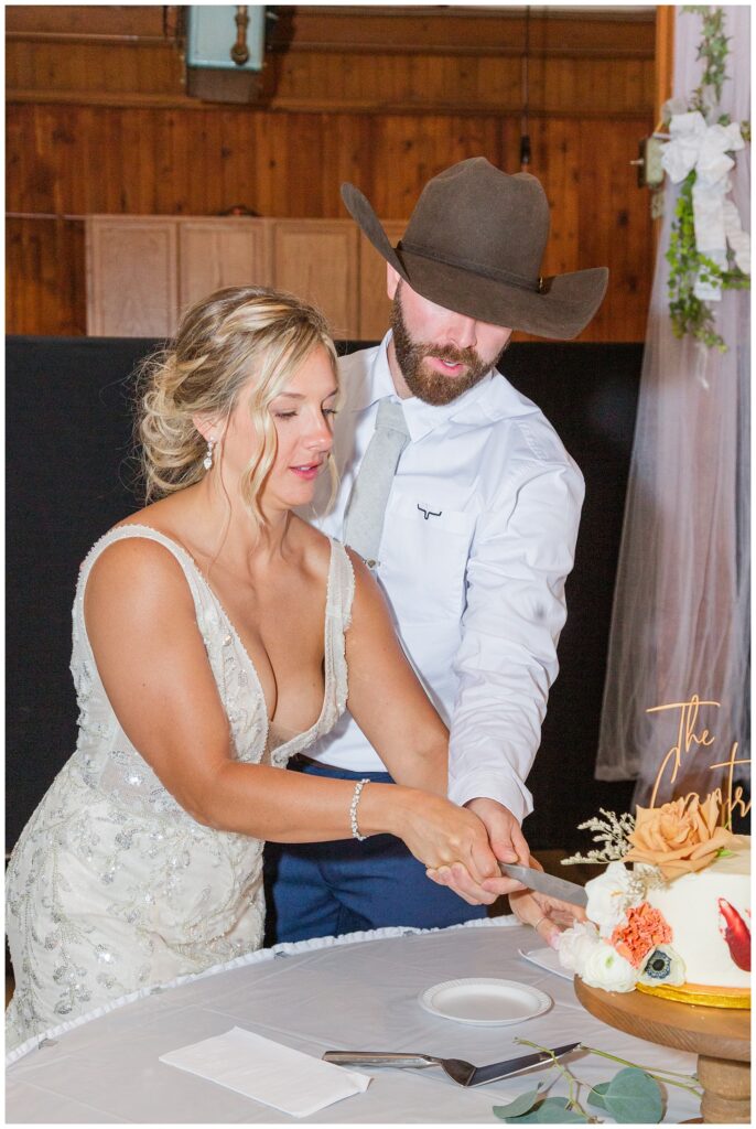 bride and groom cut cake bride at Ole Zim’s Wagon Shed wedding reception