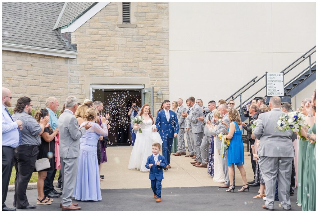 wedding guests blowing bubbles at the bride and groom after church exit 