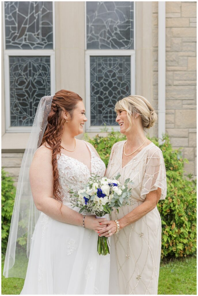 bride posing with her mom outside the church after the wedding 