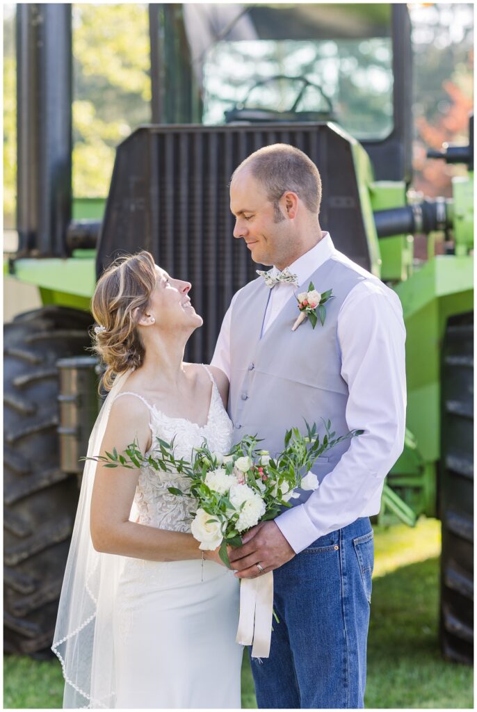 wedding couple posing in front of a green tractor at the Huron County Fairgrounds