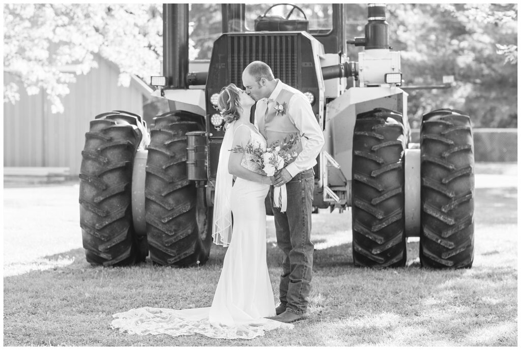 wedding couple kissing in front of a large tractor in Huron County Ohio
