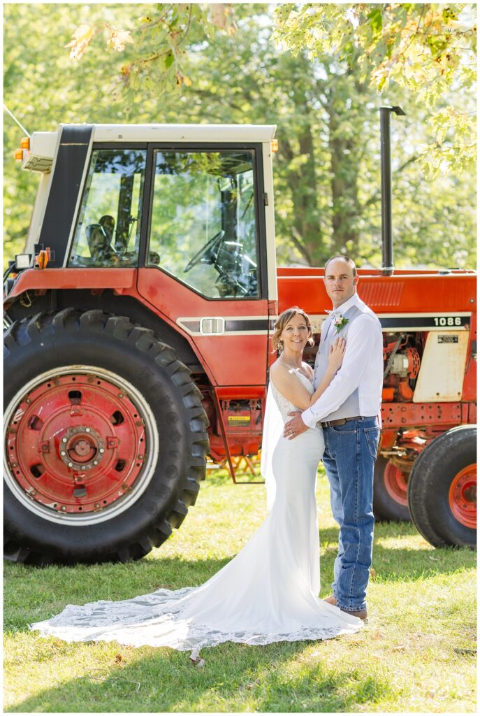 wedding couple posing in front of an old red tractor at the Huron County Fairgrounds