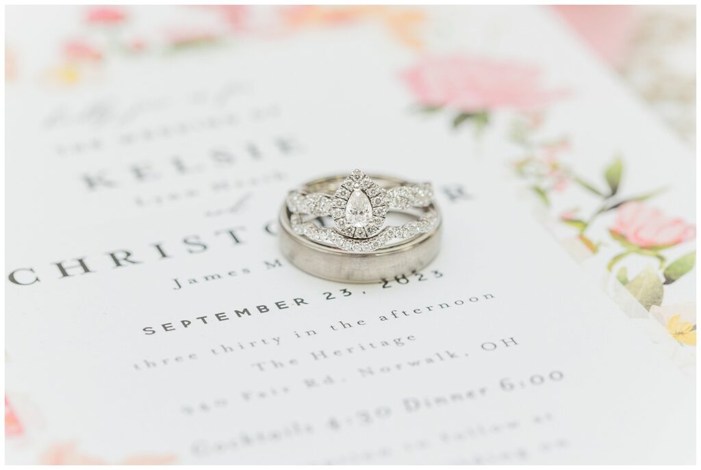 wedding rings sitting on a pink and ivory wedding invitation 