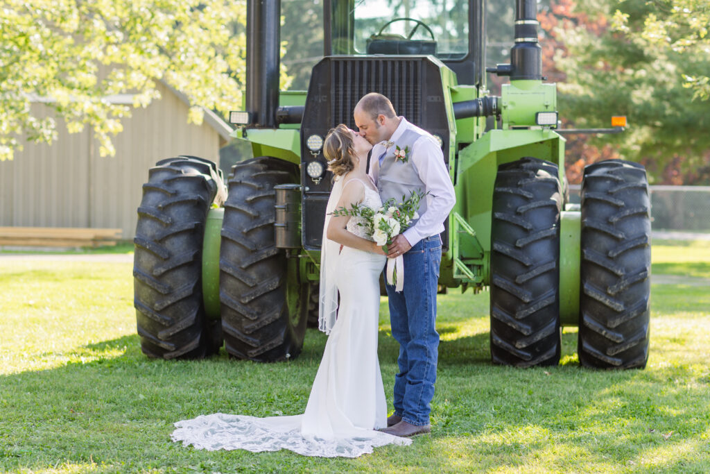 wedding couple kissing in front of a green tractor in Huron County Ohio