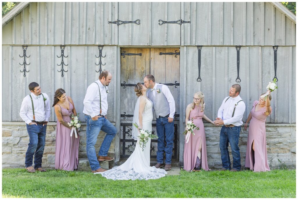 wedding party posing in front of a gray barn at Huron County Fairgrounds