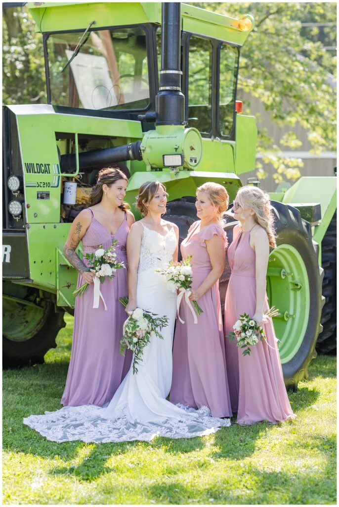 bridal party laughing in front of a large green tractor at Norwalk, Ohio wedding