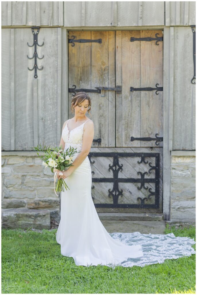 bride posing with her bouquet in front of a barn door