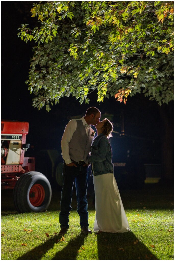 night time portraits outside next to tractors with the bride and groom