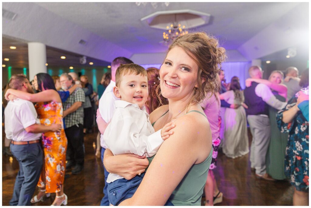 bridesmaids holding her son while dancing at wedding reception in Ohio