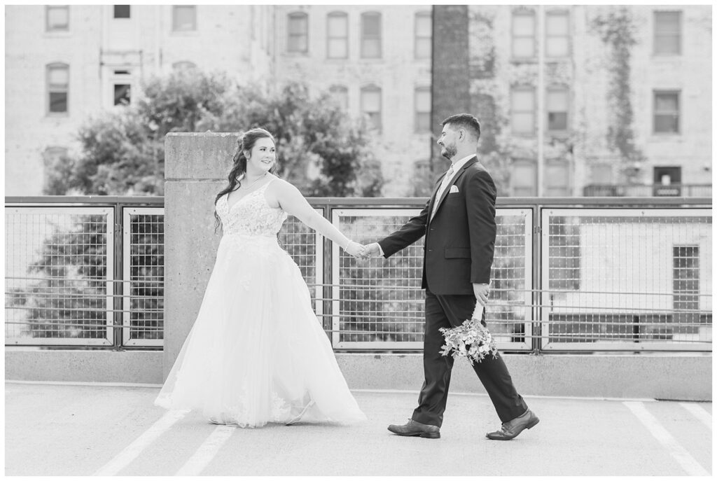 groom and bride holding hands and walking across the bridge 