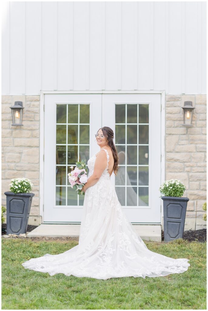 bride holding bouquet and posing outside the white double doors at venue