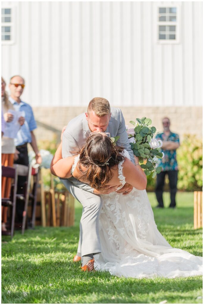 groom dips bride back for a kiss down the aisle after ceremony