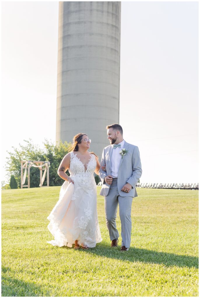 wedding couple walking in front of a white silo at a barn venue in Tiffin Ohio