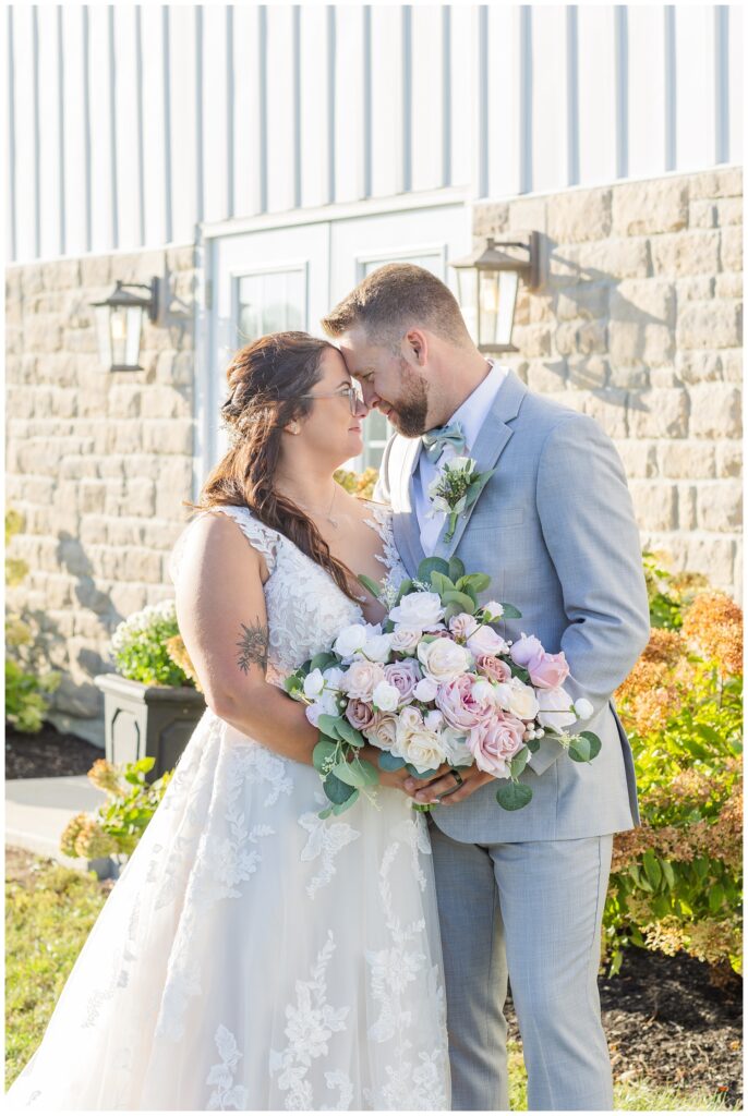wedding couple touching foreheads in front of a stone venue in Tiffin Ohio