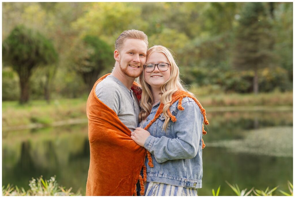 engaged couple wrapped in an orange blanket at Bradner Preserve Park