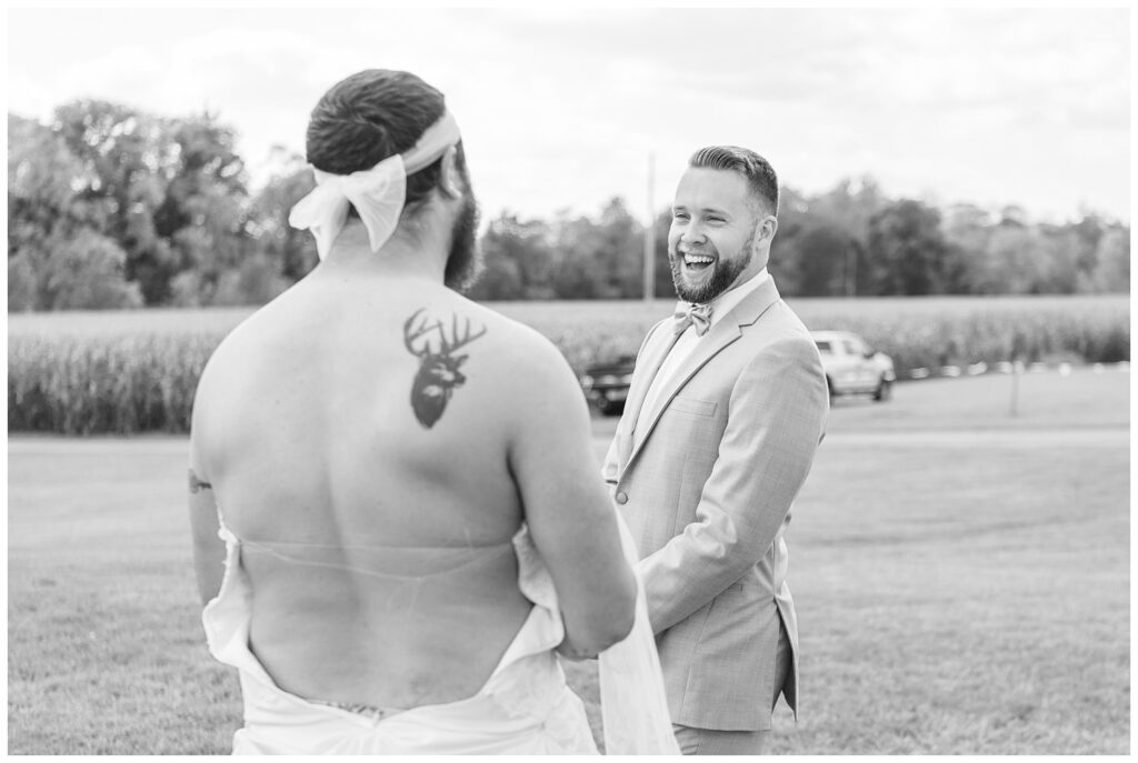 groom laughing at fake first look with the best man outside before wedding ceremony
