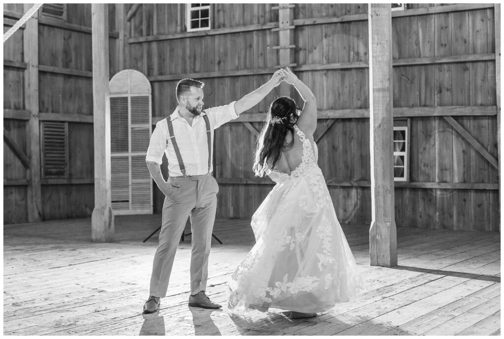 groom twirls bride during last dance at reception in barn