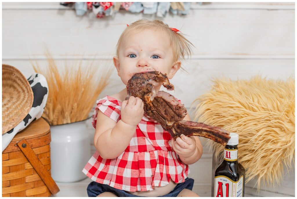 one year old eating a steak at her milestone portrait session