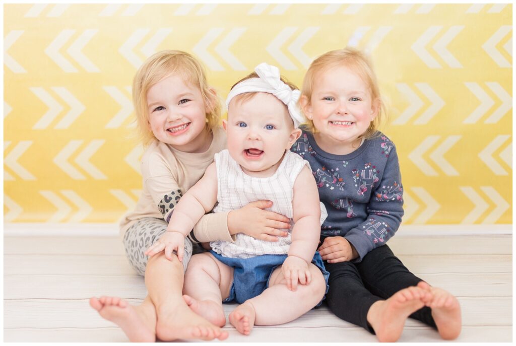baby posing with her sisters at milestone portrait session in Tiffin, Ohio