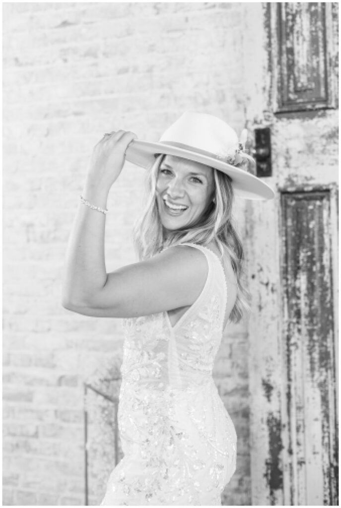 bride laughing back while tipping her white cowboy hat and wedding dress