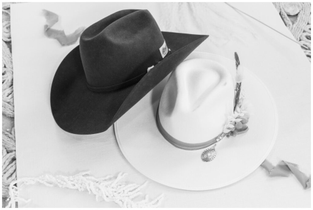 bride and groom's cowboy hats leaning against each other on a white flat mat