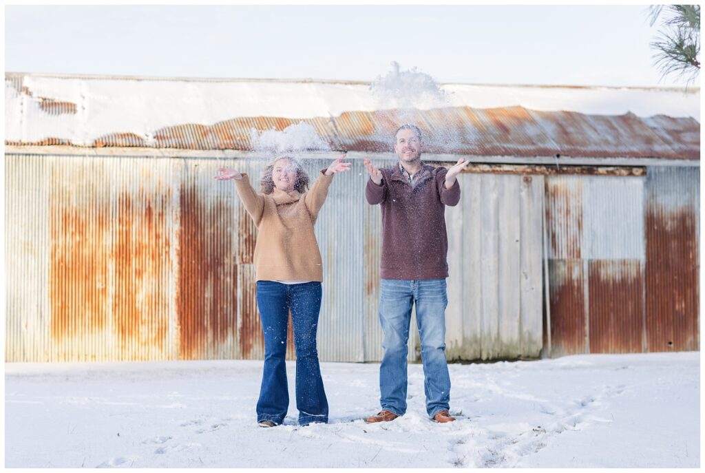 couple throwing snow up in the air during winter engagement session in Ohio