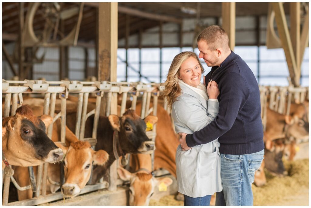 couple hugging and smiling while posing in front of cows at Jer and Bel Farms