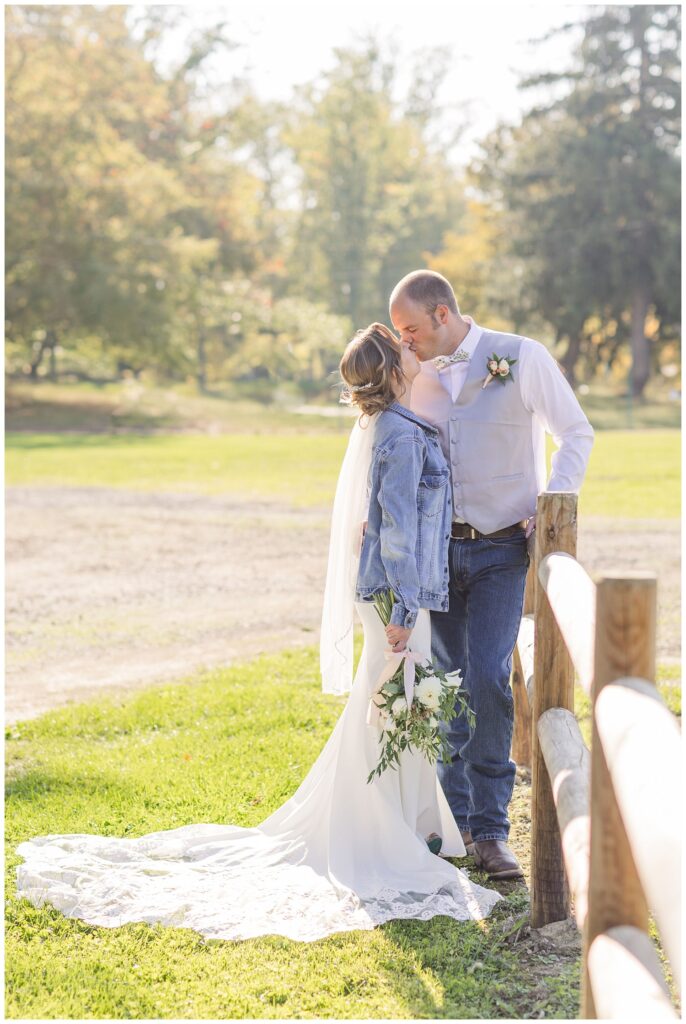 bride and groom share kiss along a fence at farm at Fremont,, Ohio wedding