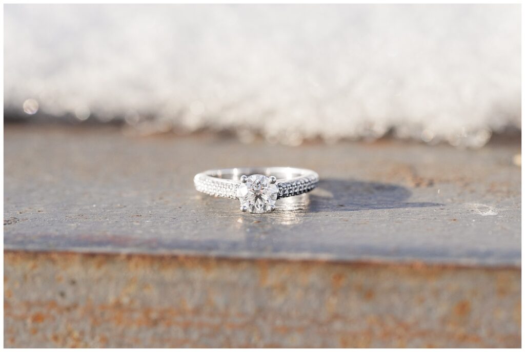 engagement ring sitting on a piece of metal next to snow
