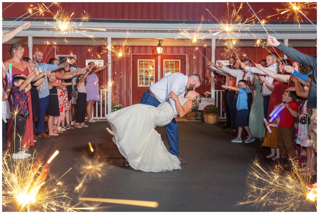 bride and groom dip back for a kiss during sparkler reception exit in Gibsonburg, Ohio