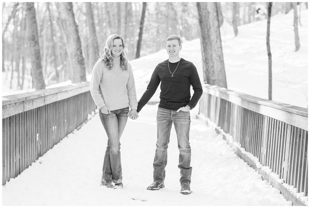 engaged couple holding hands on a snow covered bridge in Lewis Center, Ohio