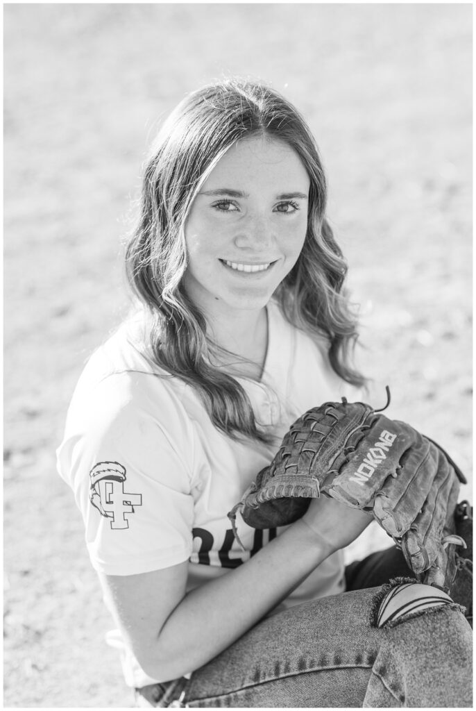girl holding her softball glove posing on the field at senior session