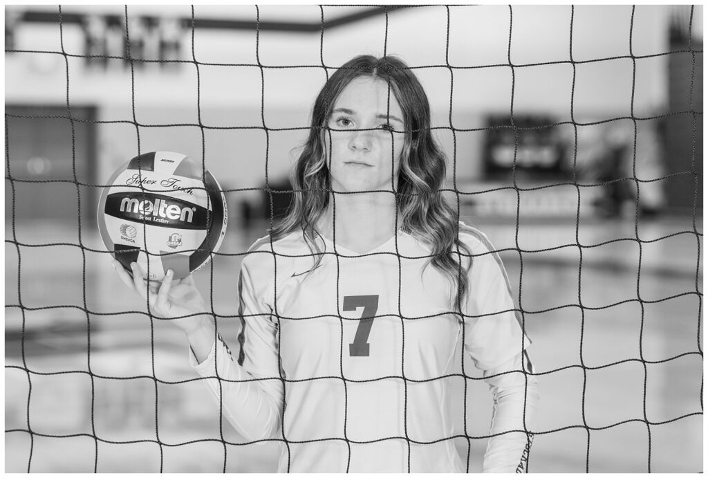 senior standing behind a volleyball net wearing her uniform at Old Fort High School