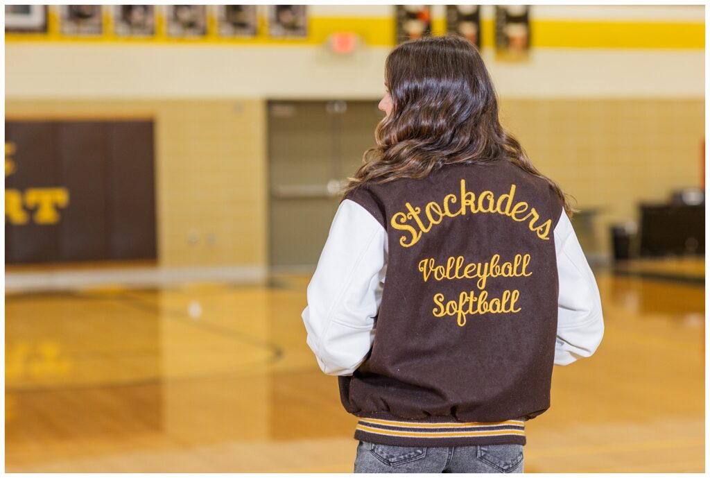senior girl wearing a letterman jacket in the gym at Old Fort High School