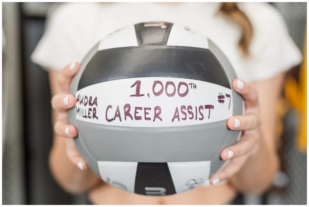 high school senior holding up a volleyball to show her volleyball career assists