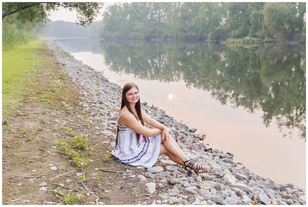 senior sitting on some rocks along a river in Castalia, Ohio