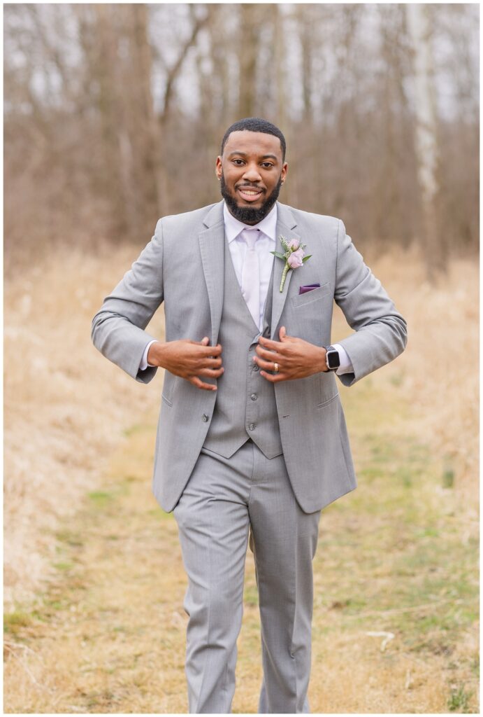 groom adjusting his jacket while posing in a field in Ohio