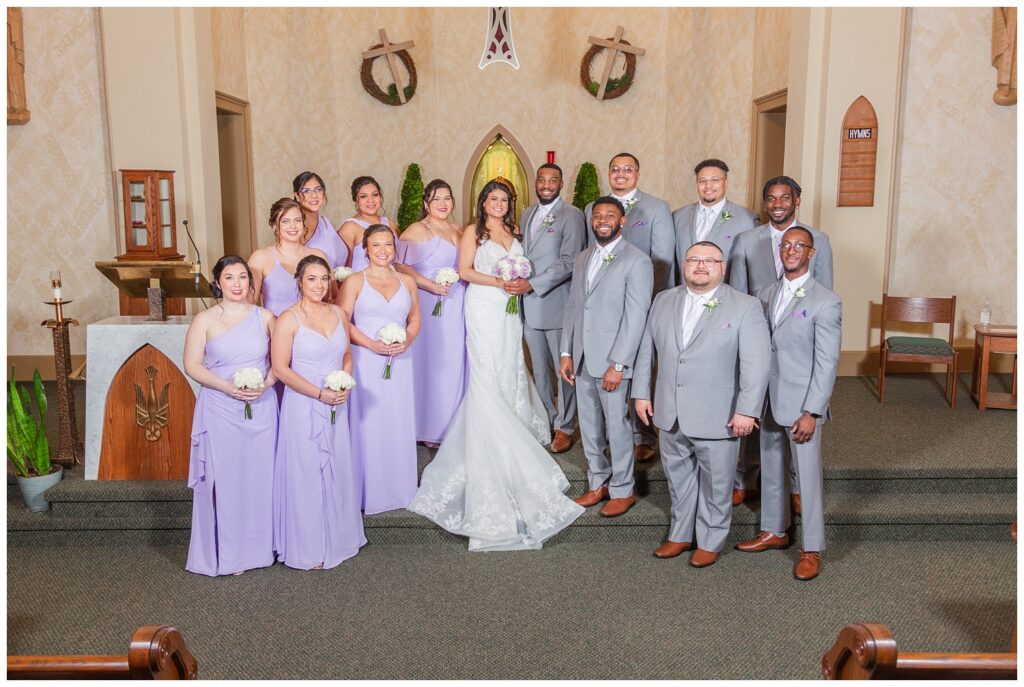 bride and groom posing with entire wedding party at Catholic church in Bradner, Ohio