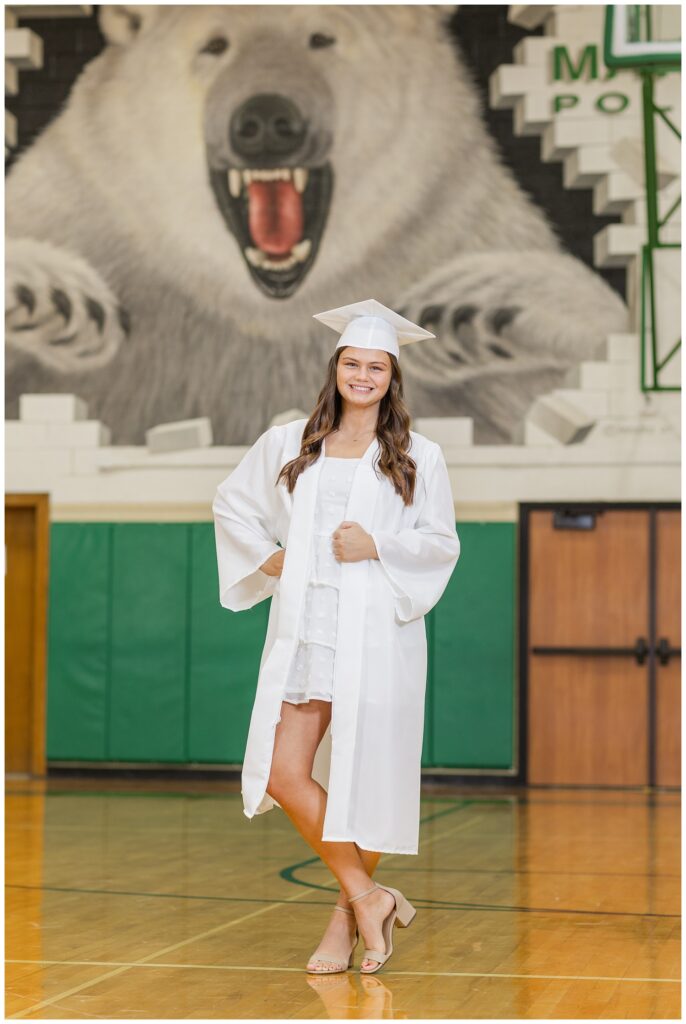 senior girl posing in her cap and gown at Margaretta High School gym