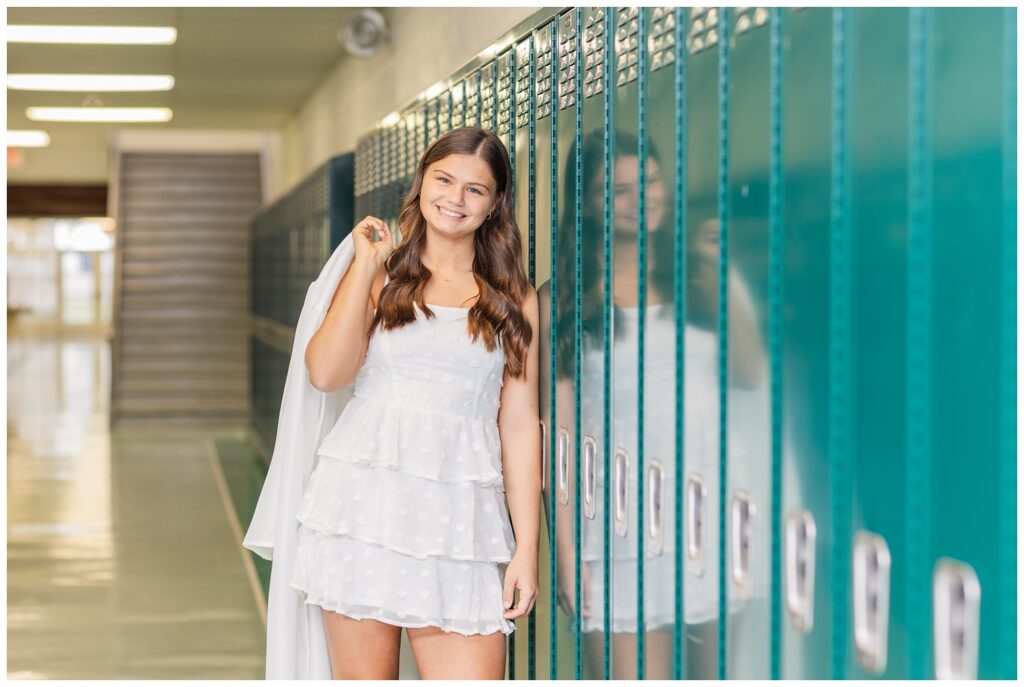 high school senior girl leaning against green lockers at her school in Sandusky