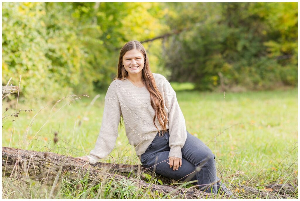 senior girl sitting on a log for portrait session in Sandusky